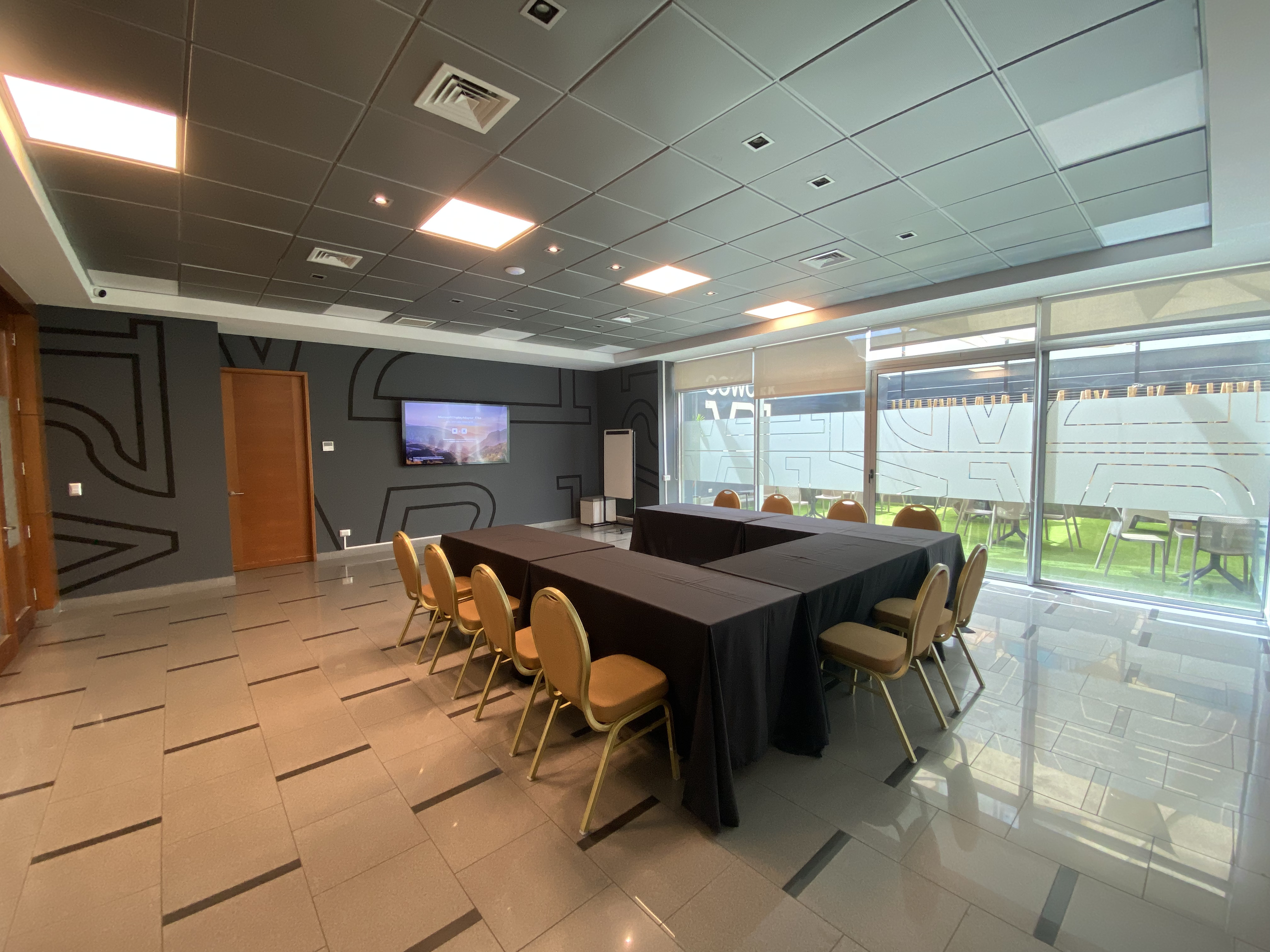 Salón Proyección con mesas en U, sillas, Smart TV y ventanales